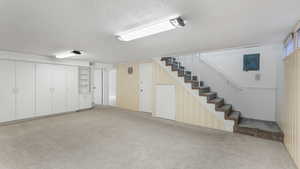 Finished below grade area featuring stairway, carpet, a textured ceiling, and electric panel