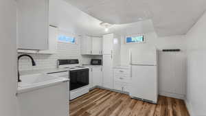 Kitchen featuring freestanding refrigerator, black microwave, a sink, range with electric stovetop, and white cabinetry