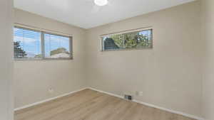 Unfurnished room featuring light wood finished floors, a ceiling fan, and baseboards