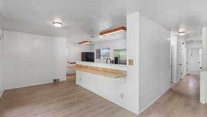 Kitchen with stainless steel fridge with ice dispenser, light wood finished floors, freestanding refrigerator, light countertops, and baseboards