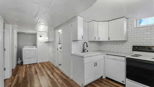 Kitchen featuring white appliances, washer / dryer, a sink, and light countertops