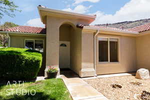Entrance to property with stucco siding, a tile roof, and a mountain view