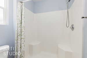 Full bathroom with a tile shower and toilet