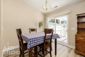 Dining space with a chandelier, light wood-type flooring, baseboards, and vaulted ceiling