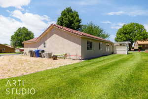 Rear view of property featuring a yard, stucco siding, and a tiled roof