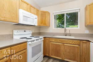 Kitchen featuring white appliances, a sink, light countertops, and wood finished floors