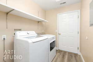 Washroom with independent washer and dryer, light wood-style floors, and baseboards