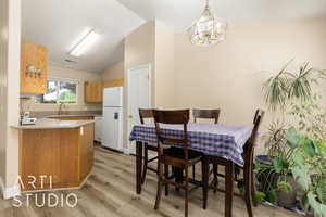 Dining space with light wood finished floors, lofted ceiling, and a chandelier