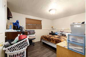 Bedroom featuring wood finished floors, a textured ceiling, and baseboards