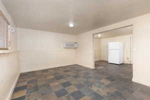 Spare room with a textured ceiling, dark stone finish flooring, and a wall unit AC