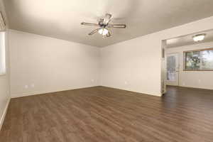 Unfurnished room with ceiling fan, dark wood-style flooring, and baseboards