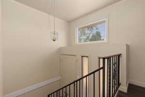 Stairway with a chandelier, wood finished floors, baseboards, and crown molding
