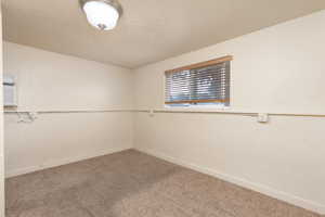 Unfurnished room with a textured ceiling, carpet, and a wall mounted AC