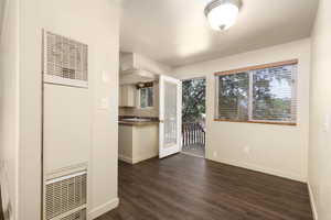 Unfurnished dining area with a heating unit, dark wood finished floors, and baseboards