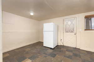 Kitchen with freestanding refrigerator and dark stone finish flooring