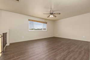 Empty room with ceiling fan, dark wood finished floors, and baseboards
