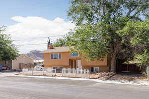 Bi-level home featuring a fenced front yard, stucco siding, and a chimney