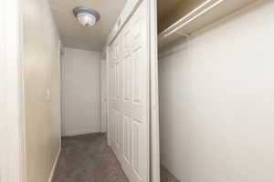 Hall featuring dark carpet and baseboards