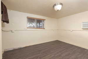 Empty room featuring a textured ceiling, dark wood finished floors, and a wall mounted air conditioner
