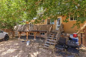 Rear view of house with stucco siding, stairs, and a deck