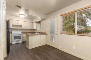 Kitchen featuring electric range, a peninsula, dark wood-type flooring, white cabinetry, and a sink