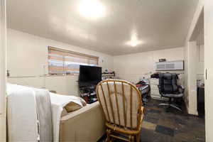 Office space featuring a textured ceiling, dark stone finish flooring, and a wall mounted air conditioner