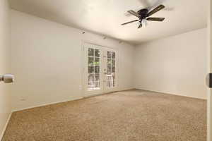 Carpeted spare room featuring french doors, ceiling fan, and baseboards