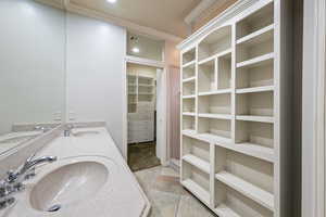 Full bath with double vanity, crown molding, a walk in closet, and tile patterned floors