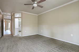 Carpeted empty room featuring ornamental molding and a ceiling fan
