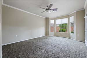 Spare room with ornamental molding, a ceiling fan, and carpet floors