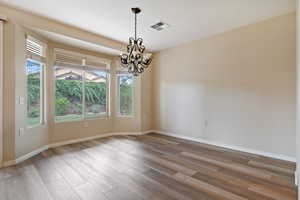 Empty room with a chandelier and wood finished floors