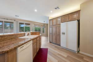 Kitchen featuring white appliances, light wood-style flooring, brown cabinets, a chandelier, and recessed lighting