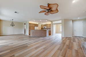 Unfurnished living room with recessed lighting, ceiling fan, light wood-type flooring, and a chandelier