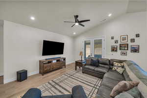 Living room featuring lofted ceiling, a ceiling fan, light wood-style floors, recessed lighting, and french doors