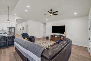 Living area featuring a ceiling fan, light wood-style flooring, lofted ceiling, and recessed lighting