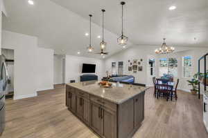 Kitchen with lofted ceiling, a chandelier, recessed lighting, light wood-style floors, and hanging light fixtures