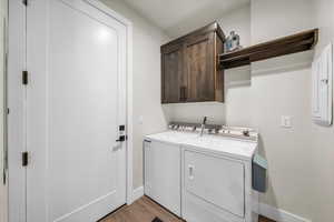 Washroom featuring washer and dryer, cabinet space, and light wood finished floors