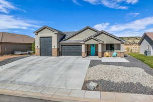 View of front of property with an attached garage, stone siding, concrete driveway, and stucco siding