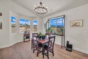 Dining room featuring a chandelier, light wood-style flooring, vaulted ceiling, and a mountain view