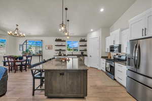 Kitchen with appliances with stainless steel finishes, open shelves, a center island, white cabinetry, and recessed lighting