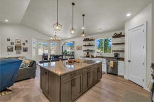 Kitchen with stainless steel dishwasher, open shelves, a chandelier, open floor plan, and light wood-style floors