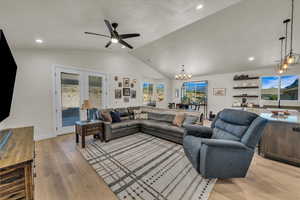 Living area with a chandelier, vaulted ceiling, light wood-style floors, ceiling fan, and recessed lighting