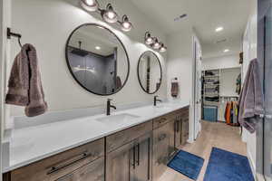 Bathroom featuring double vanity, wood finished floors, a stall shower, and a walk in closet