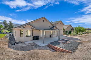 Back of house with a fire pit, a patio area, and stucco siding