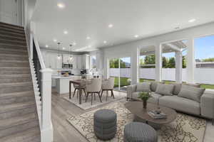 Living room featuring light wood-style flooring, stairs, and recessed lighting