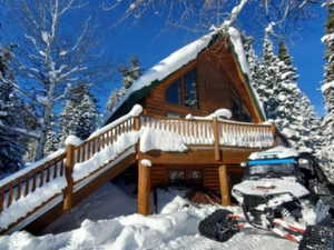 View of snowy exterior featuring a wooden deck and log exterior