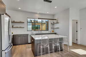 Kitchen with freestanding refrigerator, open shelves, stainless steel dishwasher, modern cabinets, and recessed lighting