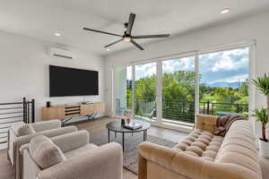 Living area featuring an AC wall unit, ceiling fan, light wood-style flooring, and recessed lighting