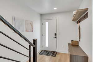 Foyer featuring light wood-style floors, stairway, and recessed lighting