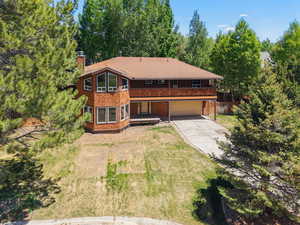Rustic home featuring concrete driveway, a chimney, and an attached garage